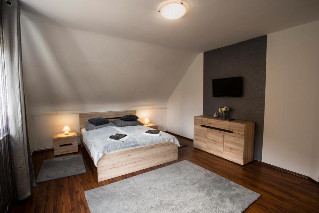 - une chambre avec un lit, 2 tables de chevet et une télévision dans l'établissement Szitakötő Apartman, à Eger