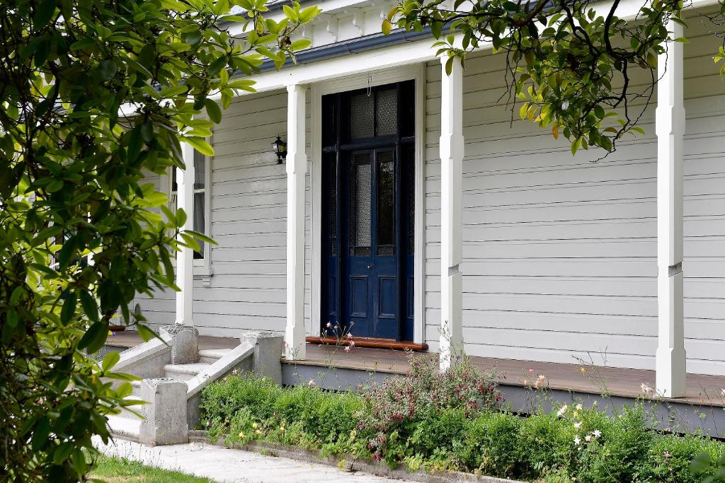 Biały dom z niebieskimi drzwiami i schodami w obiekcie Harold House w mieście Reefton