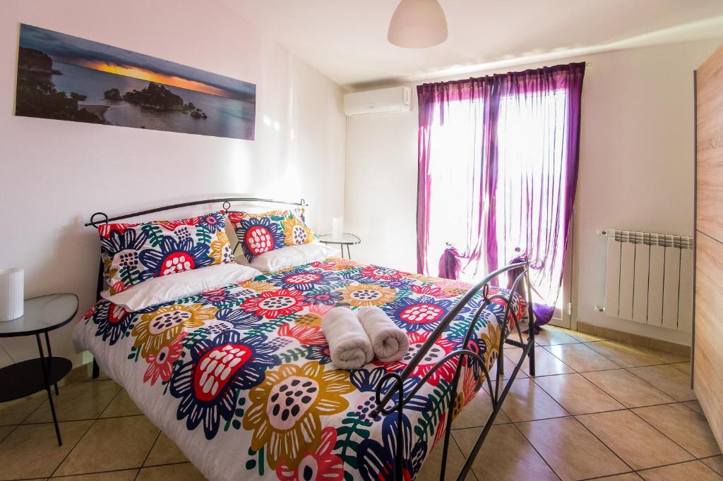 1 dormitorio con 1 cama con un edredón colorido en New Naxos Village, en Giardini Naxos