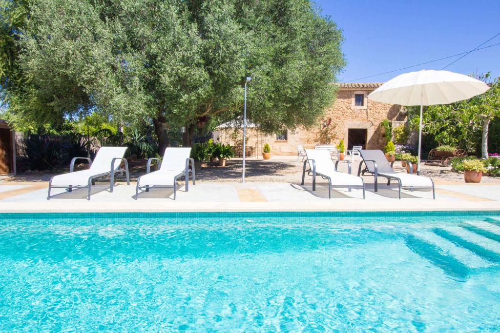 een zwembad met stoelen en een parasol bij Preciosa Finca rustica con A/C y piscina exclusiva in Algaida