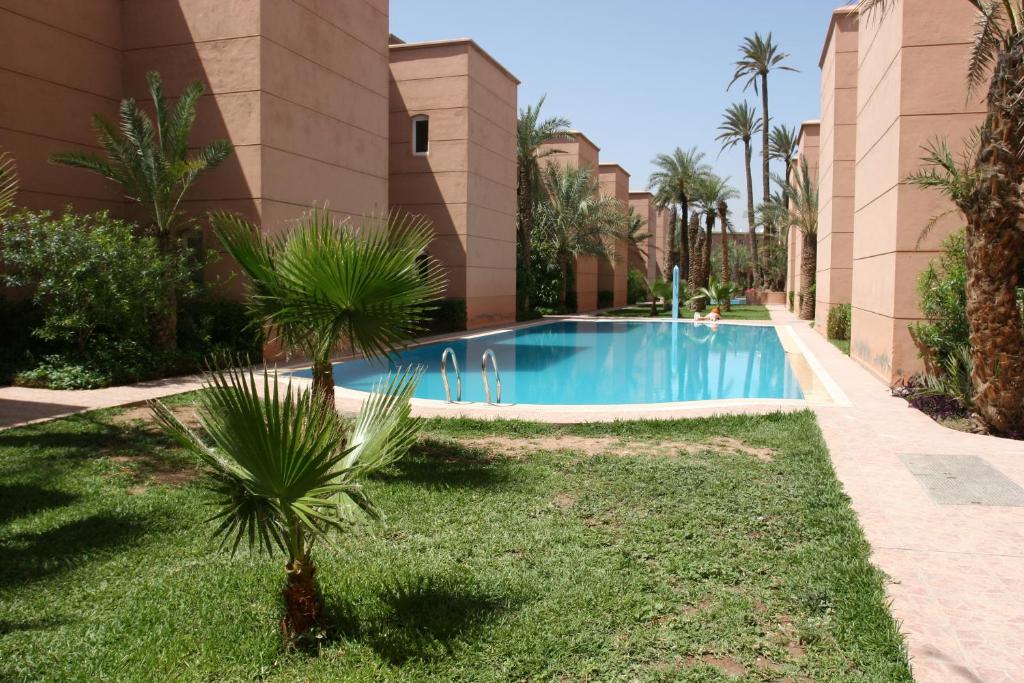 basen przed budynkiem z palmami w obiekcie Résidence alqaria assiyahiya w Marakeszu