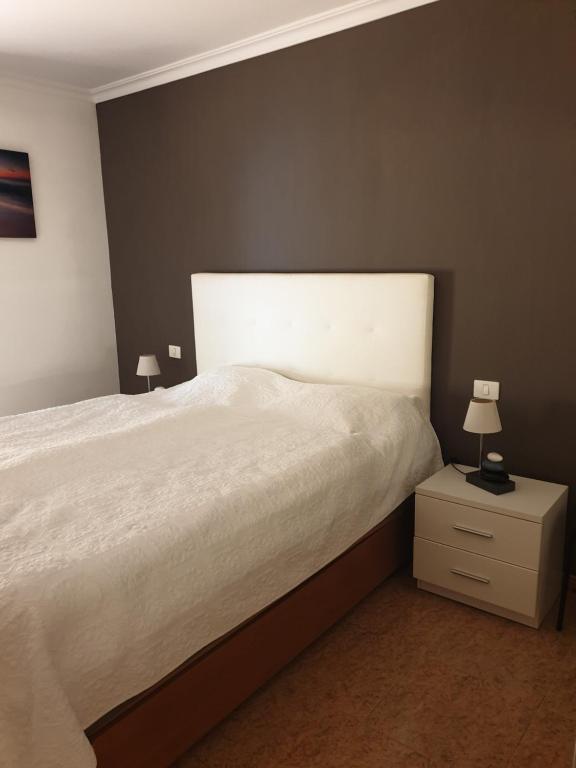 コスタ・カルマにあるLa Cabaña - Fuerteventuraのベッドルーム1室(白いベッド1台、ナイトスタンド、ランプ2つ付)