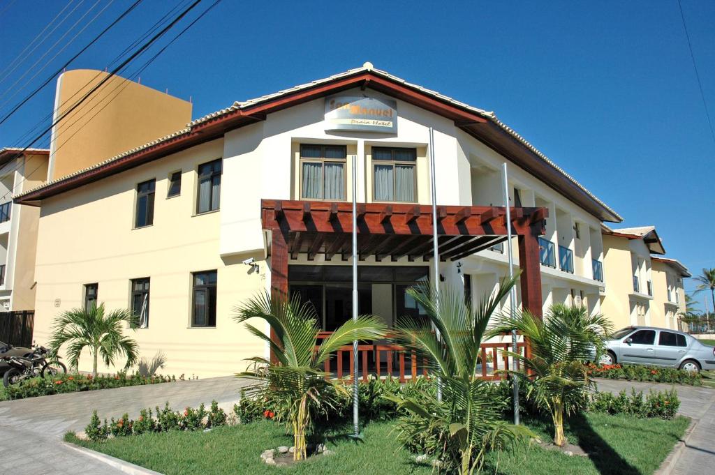 un gran edificio blanco con palmeras delante en San Manuel Praia Hotel, en Aracaju