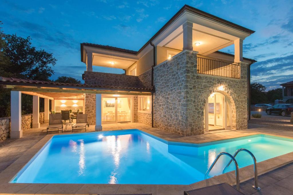 a villa with a swimming pool in front of a house at Villa Diamond - Muraj Krk in Kornić