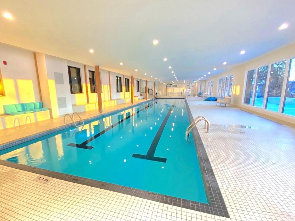a large swimming pool with blue water in a building at Auberge Des Îles in Saint-Gédéon