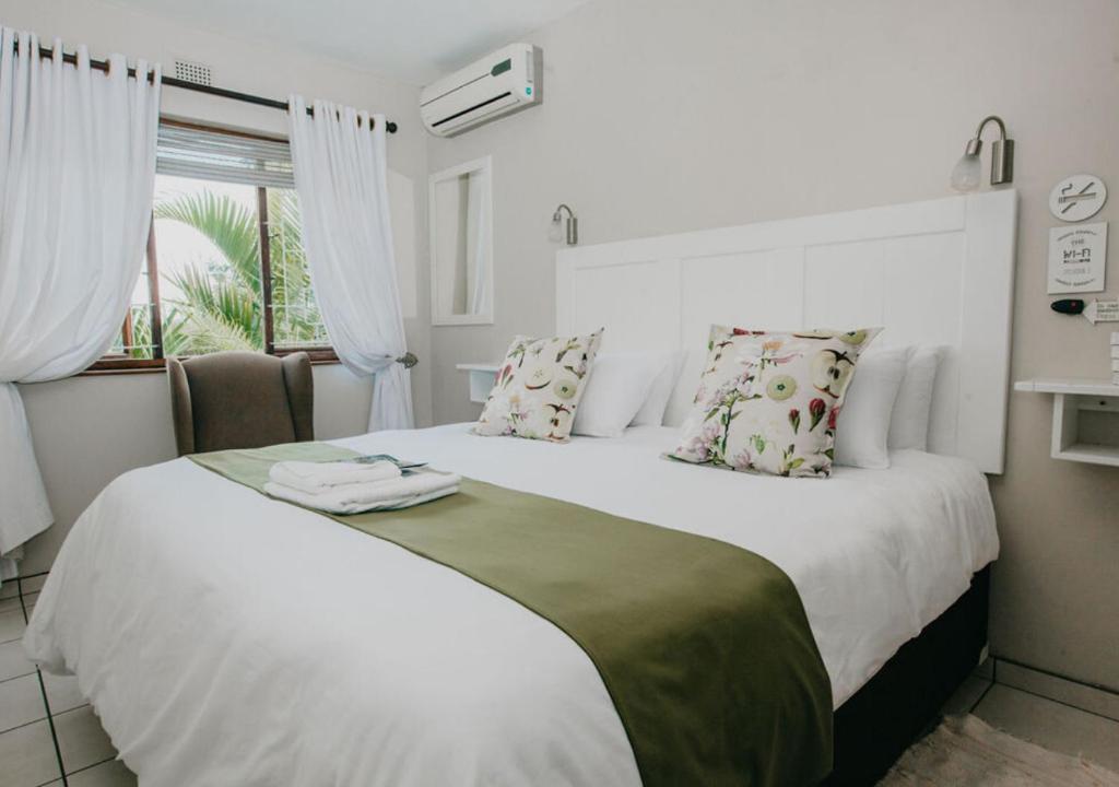 ein Schlafzimmer mit einem großen weißen Bett mit Kissen und einem Fenster in der Unterkunft Sylvern Bed and Breakfast in Durban