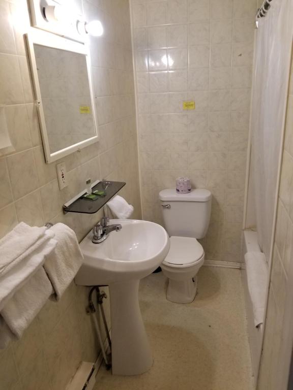 a white bathroom with a toilet and a sink at Richard lake motel in Coniston