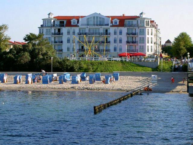 a beach with chairs and a building in the background at Apartmenthaus Atlantik in Kühlungsborn