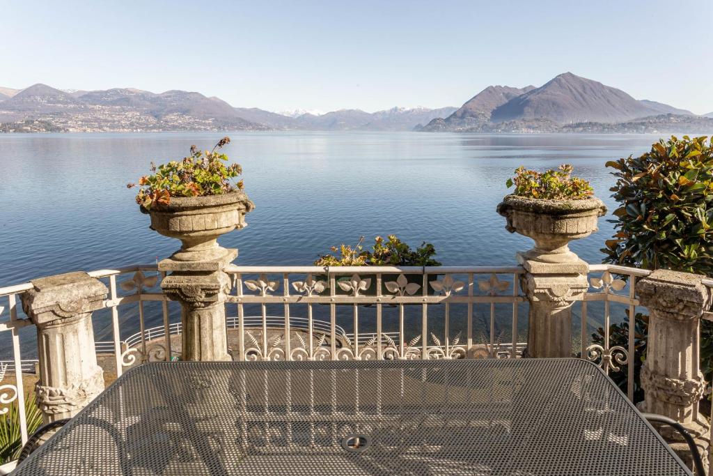 a table and two planters on a balcony overlooking a lake at Villa Niobe - Exclusive Lakefront Apartment With Private Beach in Stresa
