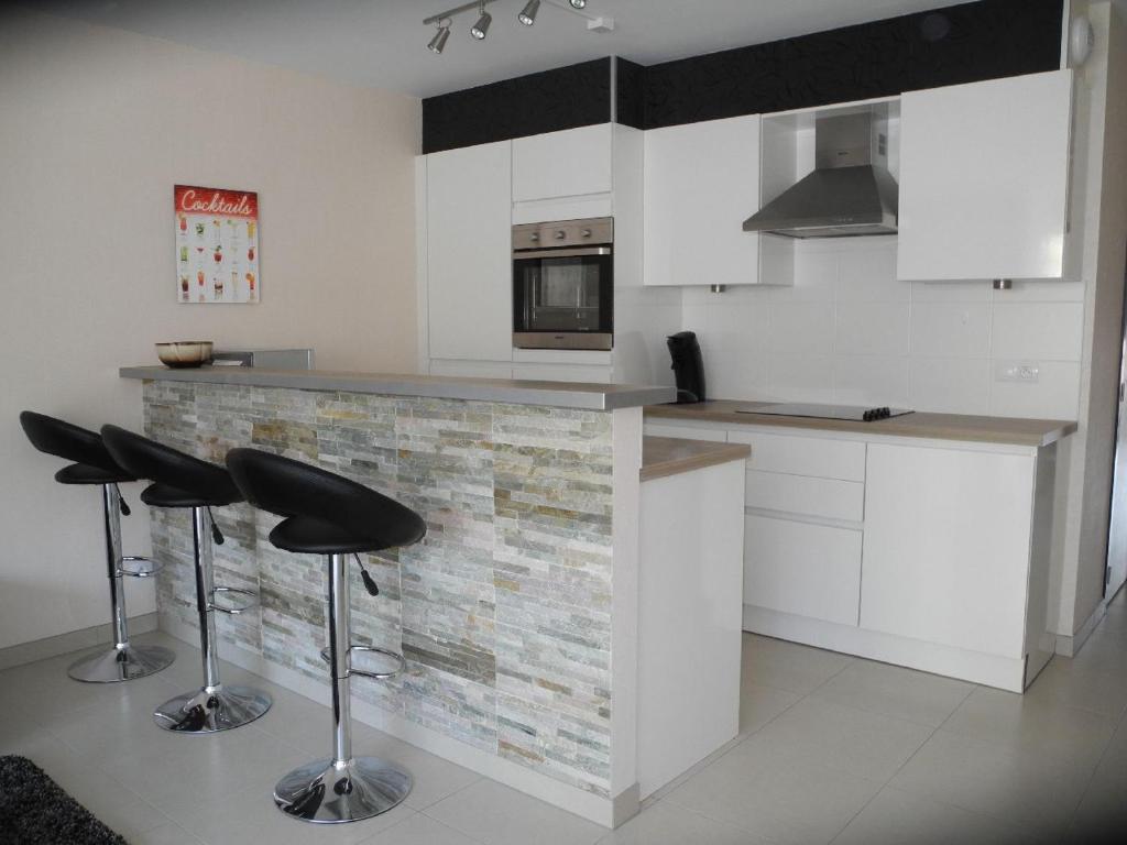 a kitchen with white cabinets and black stools in it at Margaux in De Panne