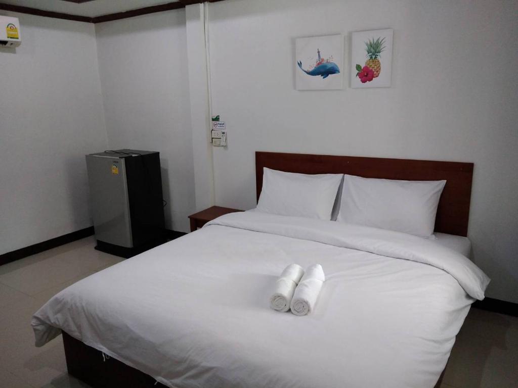 un letto bianco con due asciugamani bianchi di ณ สุข รีสอร์ท (Nasuk resort) a Khon Kaen