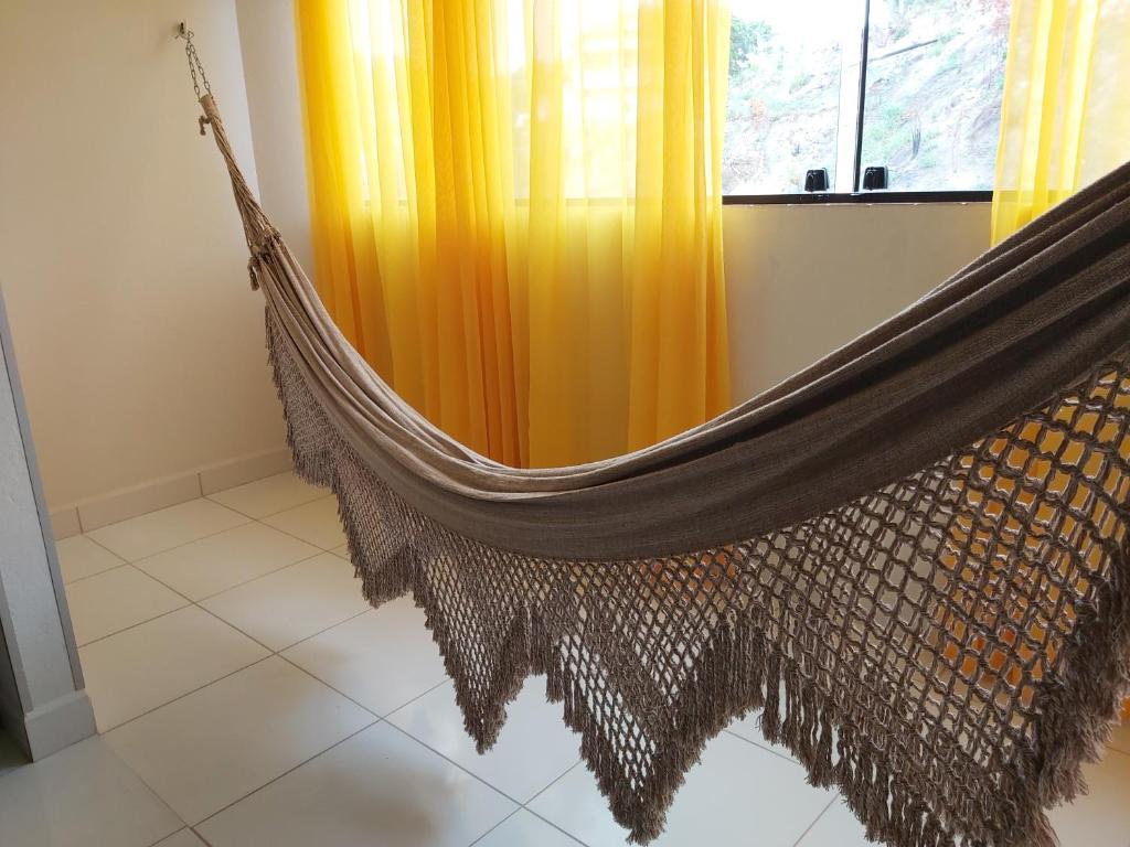 a hammock in a room with a window at Maragogi Apartamentos e Suites in Maragogi