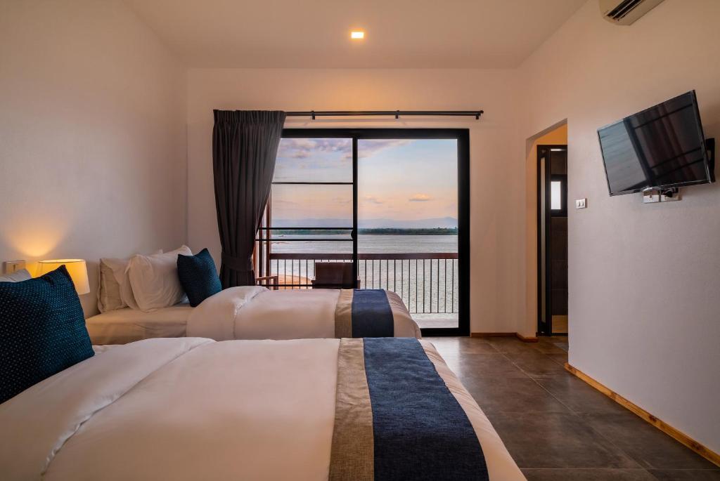 a hotel room with two beds and a view of the ocean at The Riviera Champasak in Champasak