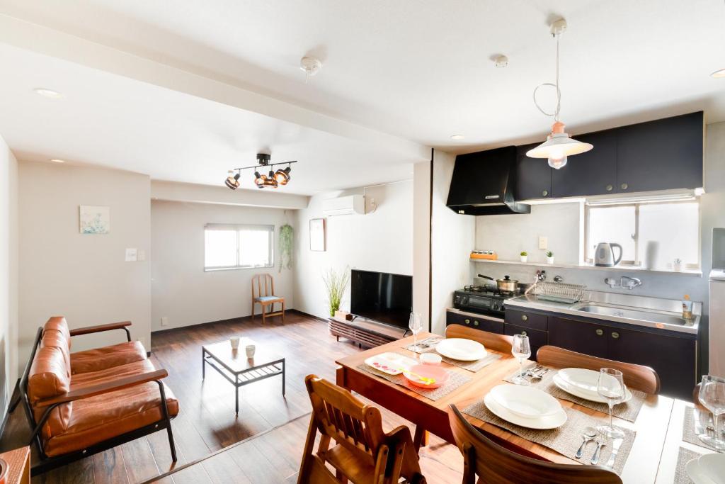a kitchen and living room with a table and chairs at Chikyuutabikazoku USJ Ⅱ in Osaka