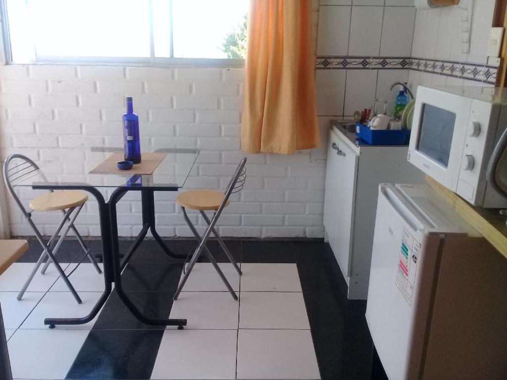 uma cozinha com uma mesa e cadeiras e um micro-ondas em Habitaciones Gabriel em Horcón