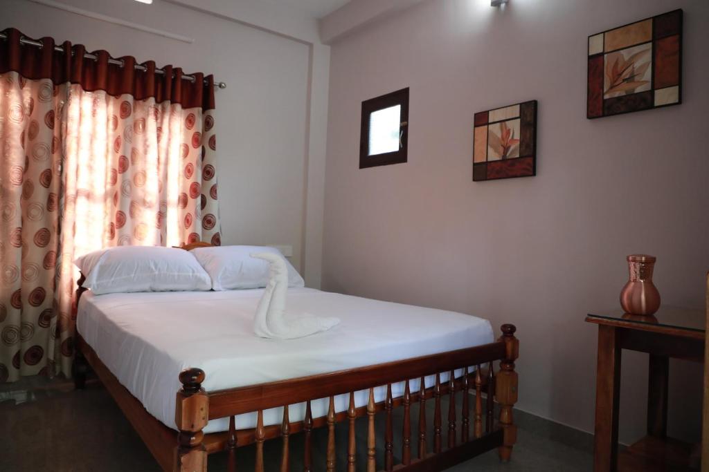 a bedroom with a bed with white sheets and a window at Villa Anandha in Trivandrum