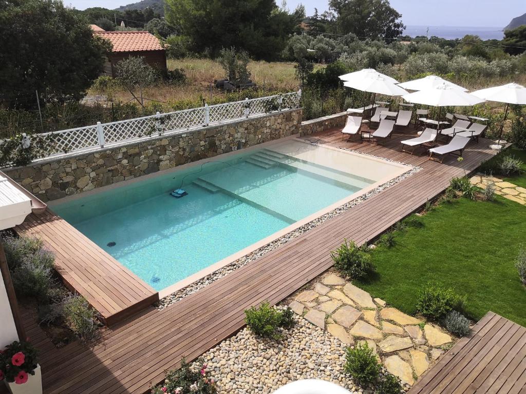 a swimming pool with chairs and umbrellas in a yard at Stile libero b&b in Lacona