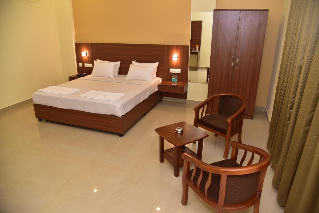 a bedroom with a bed and a chair and a table at Hotel Citywalk Residency in Mangalore