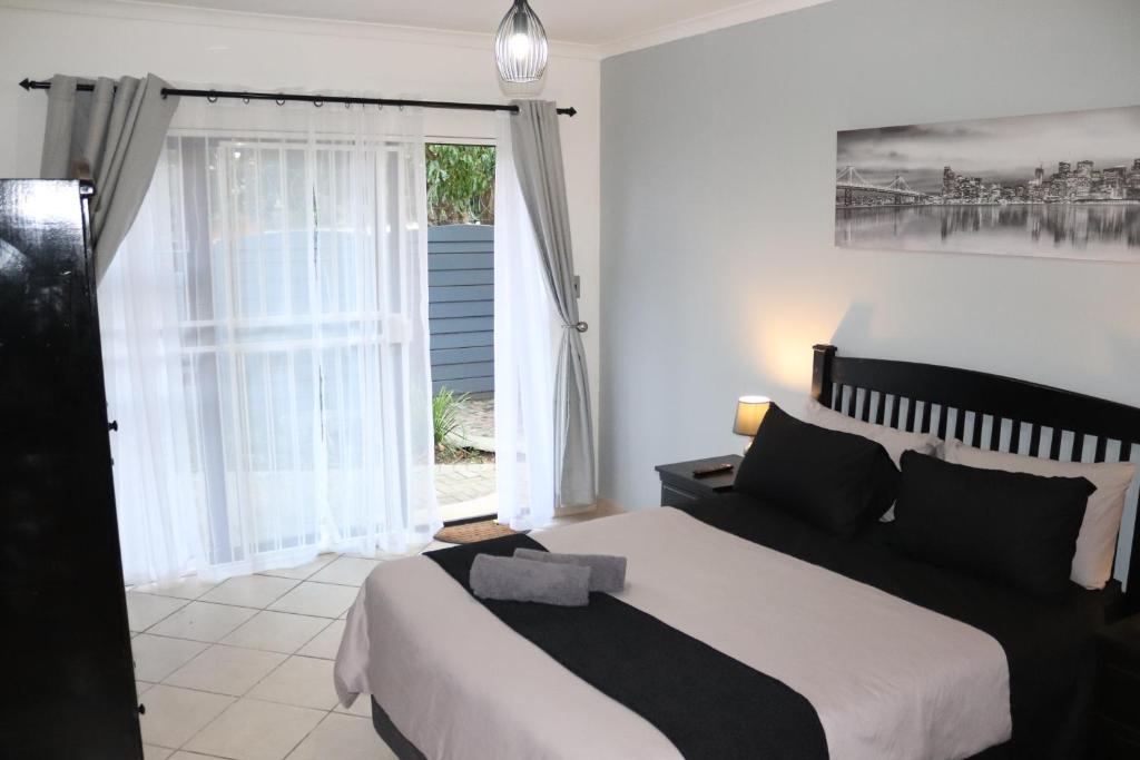 um quarto com uma cama e uma grande janela em Stay at Home Airport Lodge em Kempton Park