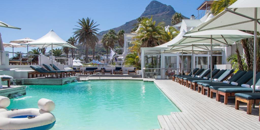 a swimming pool with lounge chairs and a resort at Adventure Pad at The Bay Hotel in Cape Town