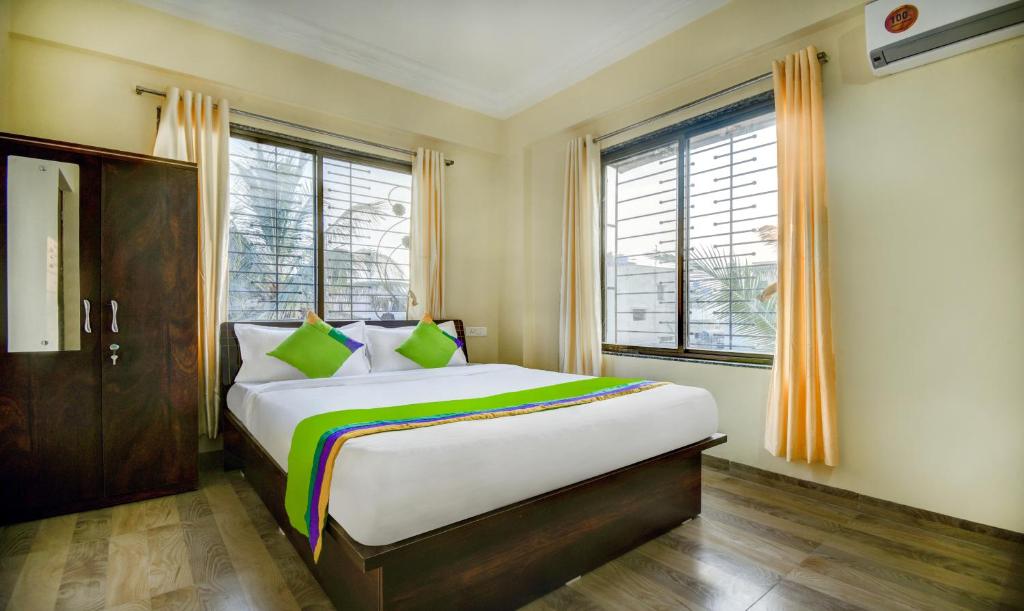 a bedroom with a large white bed with green pillows at Treebo Trend Yash Inn Kharadi in Pune