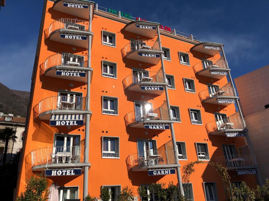 un bâtiment orange avec des balcons sur son côté dans l'établissement Hotel Garni Montaldi, à Locarno