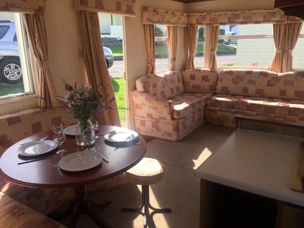 a living room with a table and some chairs at Three bedroom Hartland Caravan in Bideford
