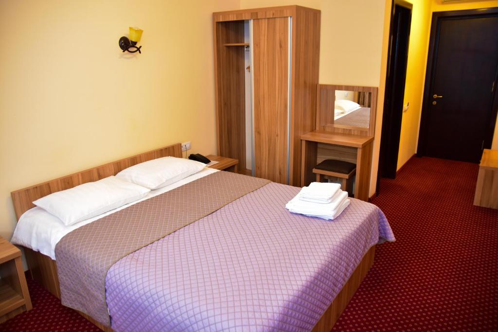 a hotel room with a bed with two towels on it at Pensiunea Bucura in Călimăneşti