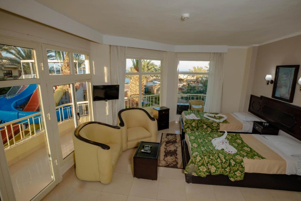 Habitación de hotel con cama y silla en Sand Beach Resort, en Hurghada
