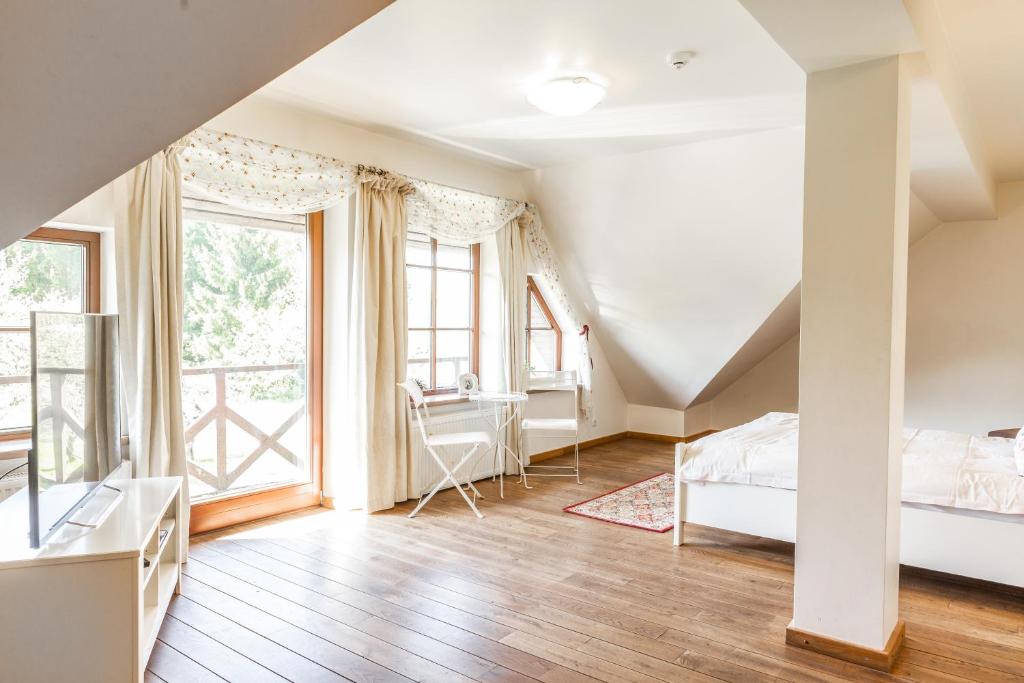 a bedroom with a bed and a desk and windows at Karlamuiza Country Hotel in Kārļi