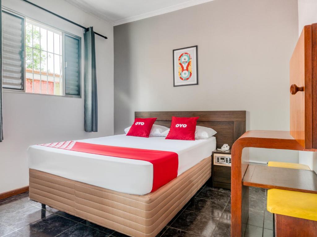 1 dormitorio con 1 cama con almohadas rojas en OYO Hotel Park Leste, São Paulo, en São Paulo