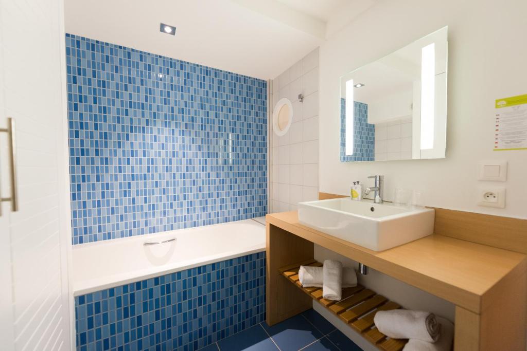 a bathroom with a sink and a blue tile wall at Hôtel La Jetée in Saint-Martin-de-Ré