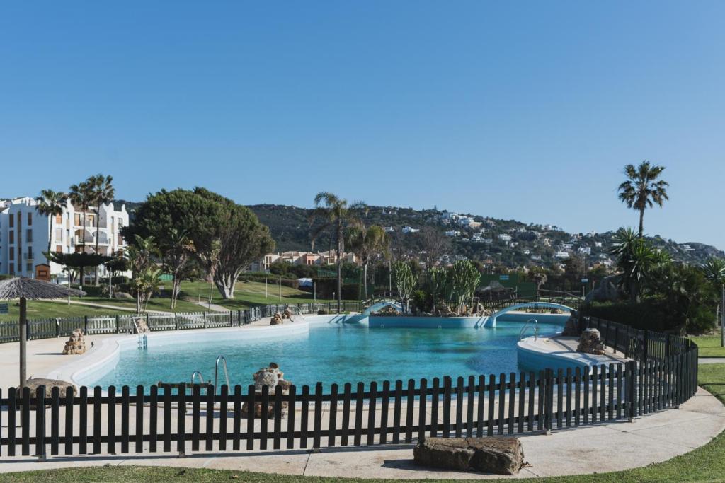 a large swimming pool in a park with a fence at Apartamento Roller - a pie de playa in Zahara de los Atunes
