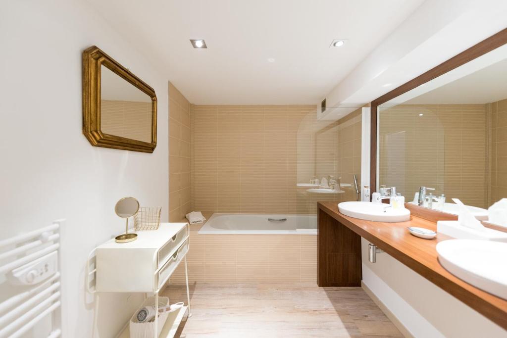 a bathroom with two sinks and a bath tub at Hôtel La Jetée in Saint-Martin-de-Ré