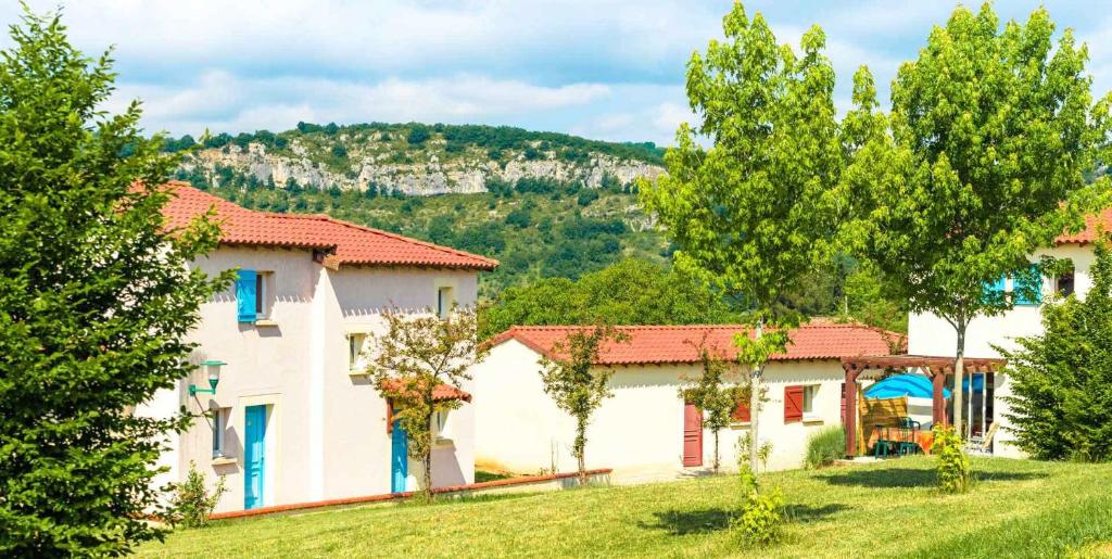 a house in a field with trees in the foreground at Le Domaine des Cazelles by Ateya Vacances in Cajarc
