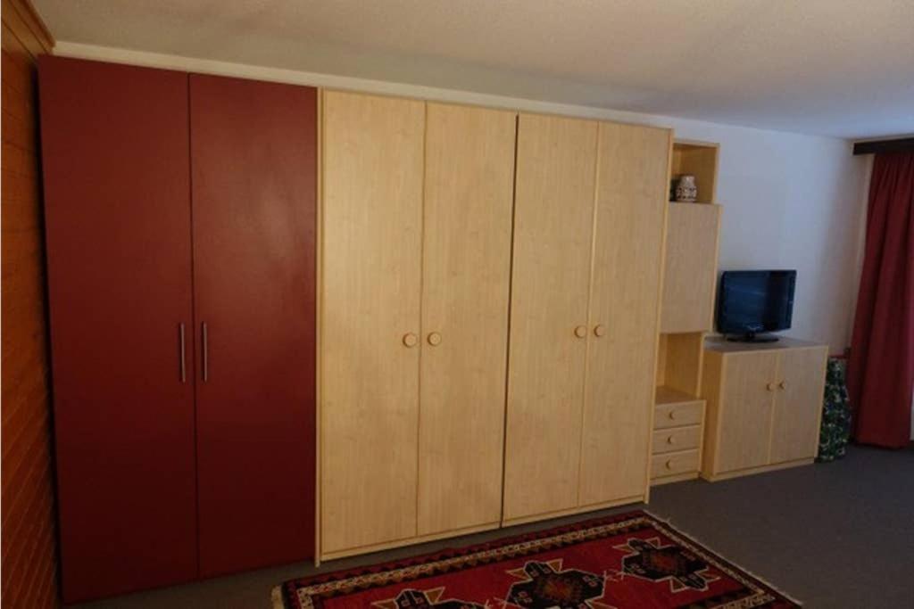 um quarto com armários de madeira, uma televisão e um tapete em Lärchenwald 610 em Leukerbad