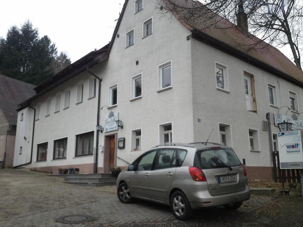 ein kleines Auto, das vor einem weißen Gebäude parkt in der Unterkunft Grüner Baum Nürnberg Brunn in Nürnberg