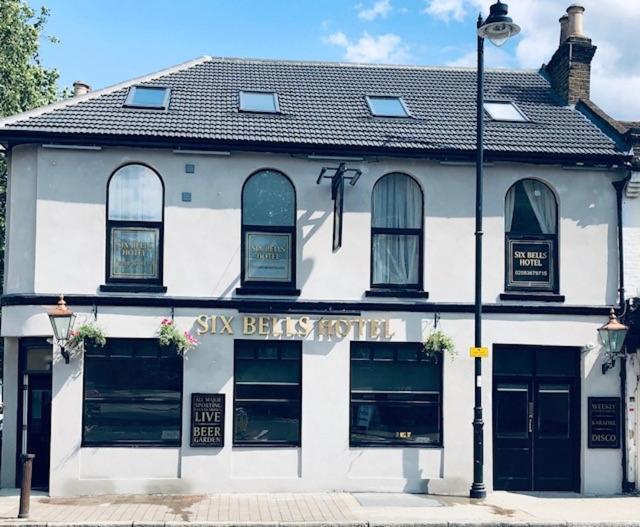 un edificio blanco con una luz de la calle delante de él en The Six Bells Hotel en Enfield