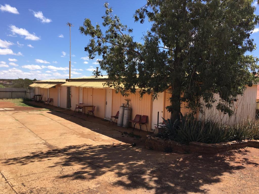 a building with chairs and a tree in front of it at Meekatharra Hotel in Meekatharra