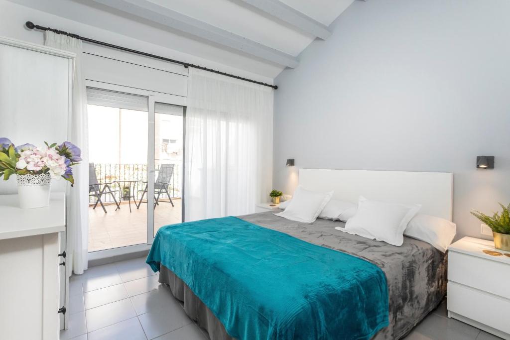 a white bedroom with a bed and a balcony at Sitges Rustic Apartments in Sitges