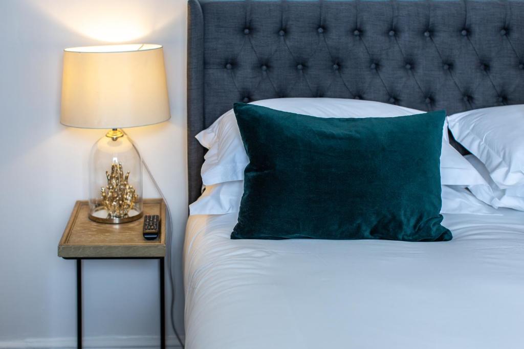 a bed with a green pillow and a nightstand with a lamp at Lyme Townhouse in Lyme Regis