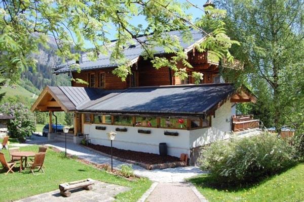 una casa con techo de gambrel con una mesa delante en Landgasthof Kirchenwirt, en Krimml