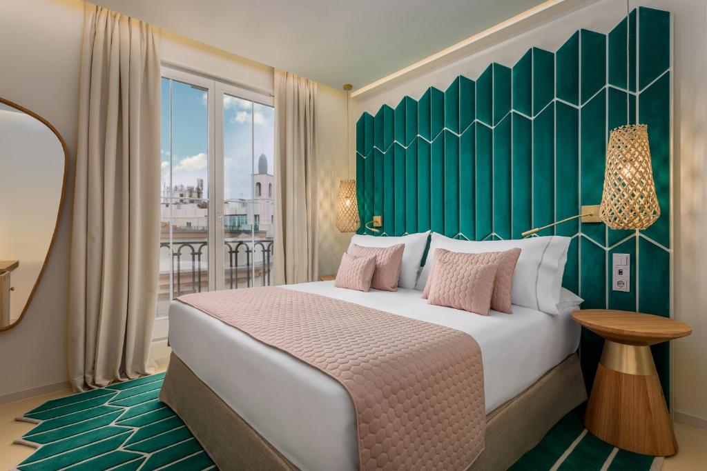 a bedroom with a large bed with a green headboard at Room Mate Macarena – Gran Vía in Madrid