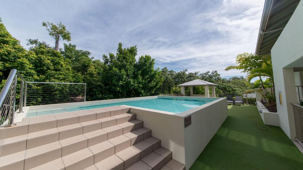 an outdoor swimming pool with a deck and a swimming poolvisorvisor at Alpha 8 on Waterson - Airlie Beach in Airlie Beach