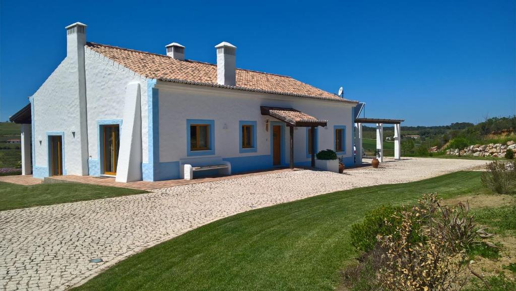 uma pequena casa branca com um jardim verde em Monte da Sapaleira em Aljezur