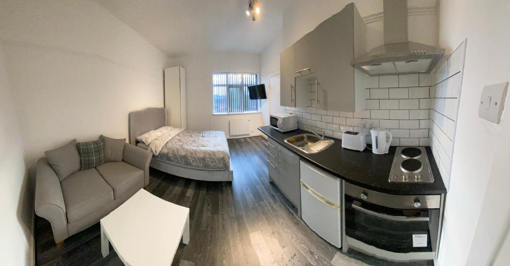 een keuken met een bank en een bed in een kamer bij Small Self Contained Studio In Sutton Coldfield in Birmingham