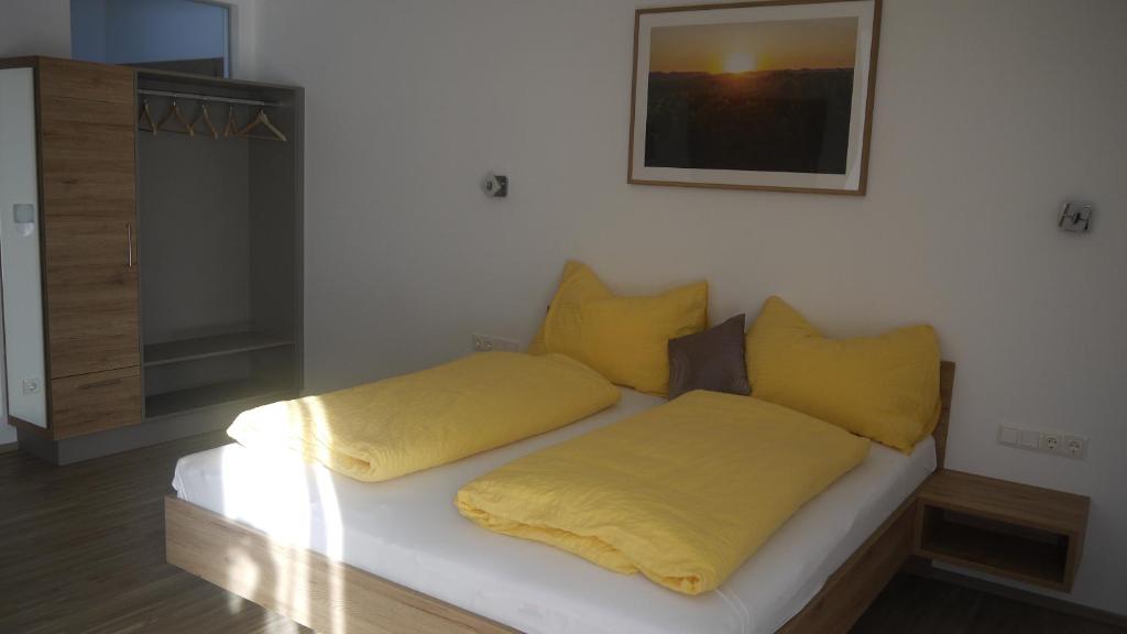 uma cama com almofadas amarelas num quarto em Weinbau Ettenauer em Rohrendorf bei Krems