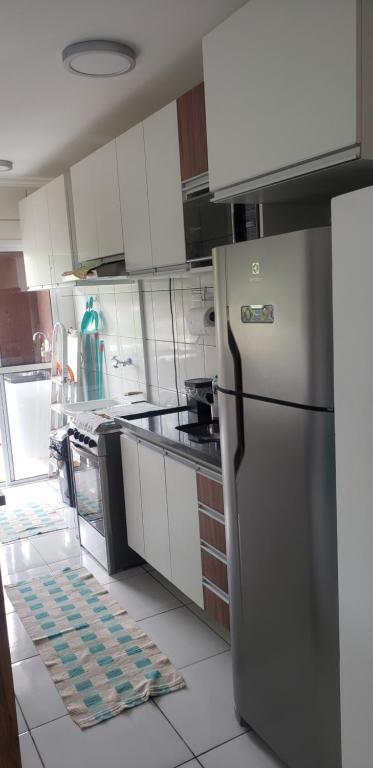 kuchnia z lodówką ze stali nierdzewnej i białymi szafkami w obiekcie Apartamento Novinho Próximo as Praias, Centro e Restaurantes - Excelente localização w mieście Ubatuba