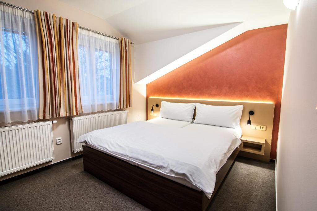 a bedroom with a large bed and two windows at Pension Bed&Breakfast in Kutná Hora