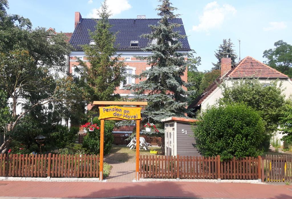 a sign in front of a house with a fence at Pension an der Havel in Havelberg